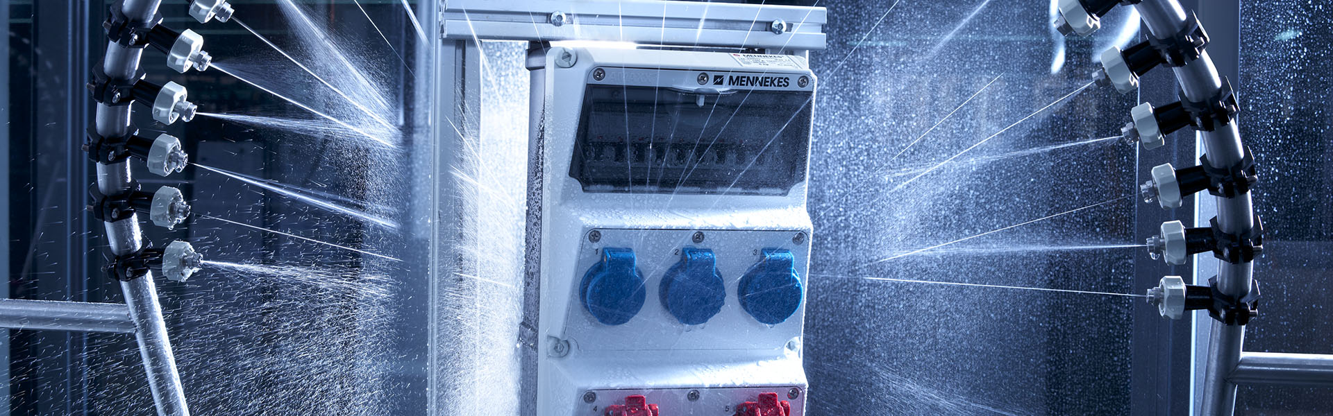 Abbildung einer AMAXX Steckdosenkombination von MENNEKES, die in einem Labor zu Qualitätszwecken mit Wasser bespritzt wird.